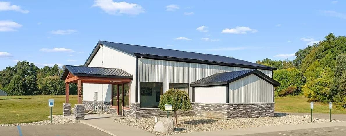 Commercial building with metal siding, stone wainscot, and a timber entry canopy