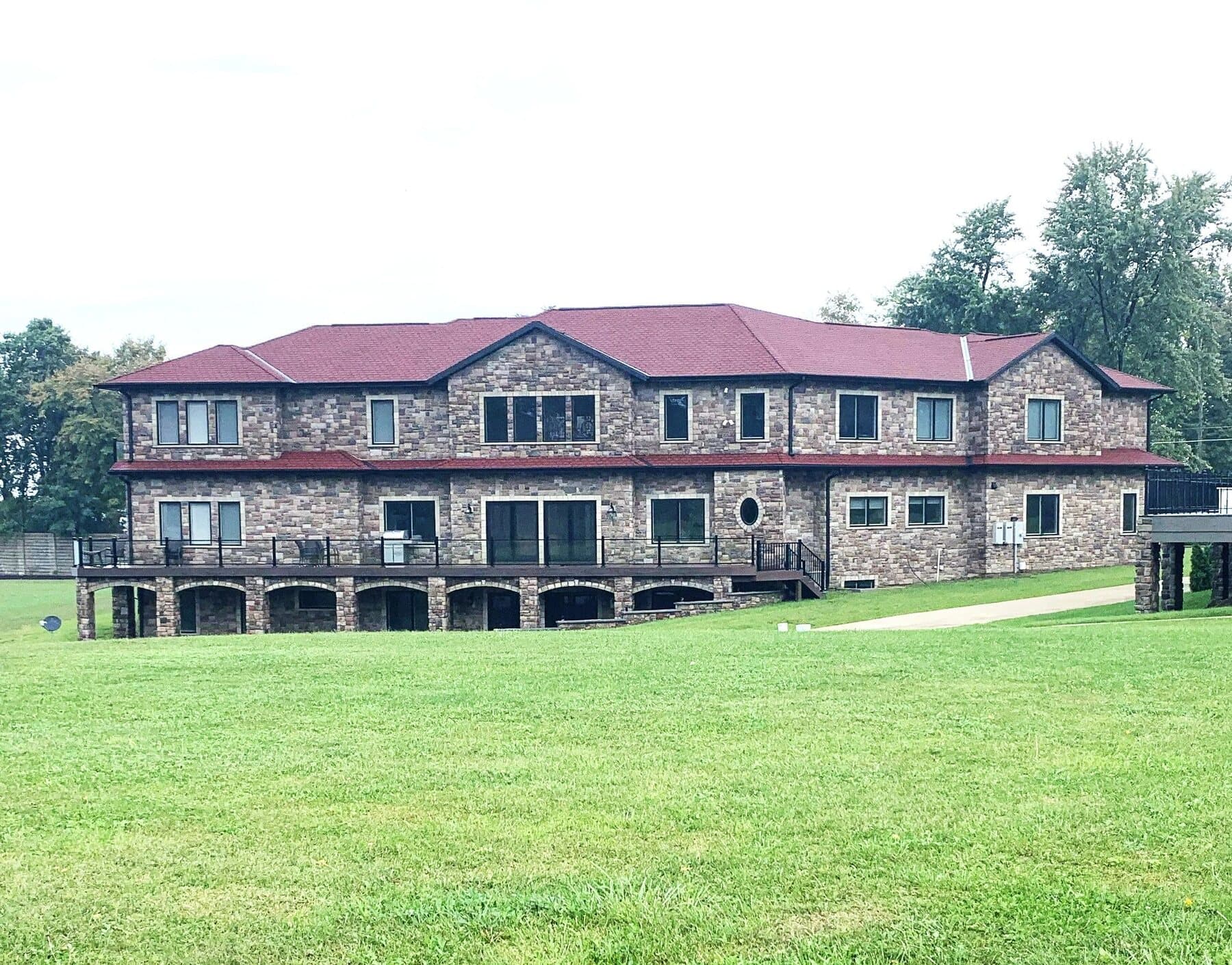 Custom home exterior with full stone facade and a red metal roof