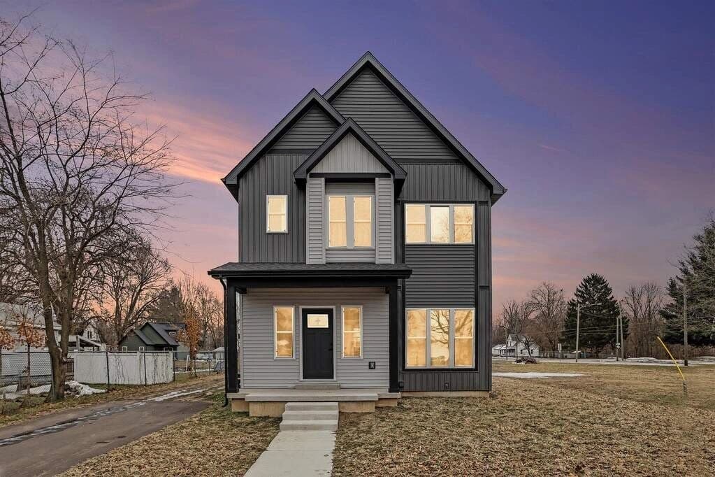 Modern two-story gray custom home at dusk with lit windows